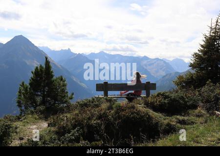 un randonneur fait une pause sur un banc devant une magnifique toile de fond de montagne Banque D'Images