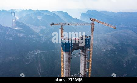 Guanling. 24 octobre 2023. Cette photo aérienne prise le 24 octobre 2023 montre une tour principale du pont du Grand canyon de Huajiang dans la province du Guizhou, dans le sud-ouest de la Chine. La dernière tour principale du pont du grand canyon Huajiang a été achevée mardi dans la province du Guizhou, dans le sud-ouest de la Chine, marquant une étape importante dans la construction du pont le plus haut du monde. Avec une hauteur conçue de 625 mètres entre le pont et la rivière Beipanjiang ci-dessous, le pont du grand canyon Huajiang devrait être le plus haut du monde après son achèvement en 2025. Crédit : Tao Liang/Xinhua/Alamy Live News Banque D'Images