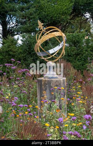 Cadran solaire de sphère armillaire dans un jardin entouré de fleurs sauvages Banque D'Images