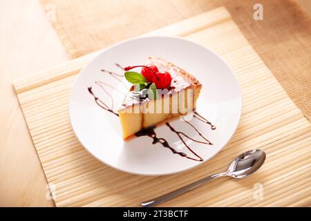 Tranche de dessert de flan maison, également connu sous le nom de crème caramel, pudding au caramel ou crème anglaise aux œufs, décoré de feuilles de menthe et de cerises, servi sur Banque D'Images