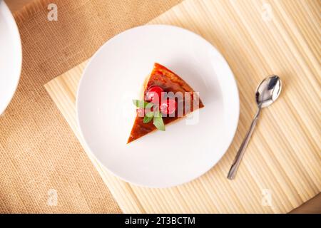 Tranche de dessert de flan maison, également connu sous le nom de crème caramel, pudding au caramel ou crème anglaise aux œufs, décoré de feuilles de menthe et de cerises, servi sur Banque D'Images