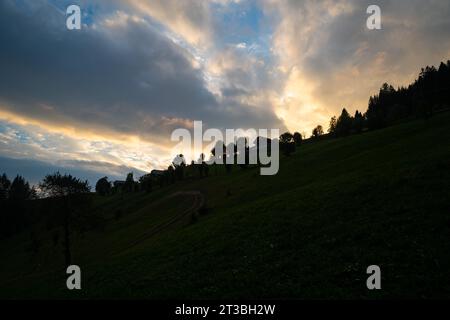 Une pente de montagne dans les Dolomites est silhouettée contre un ciel nuageux coloré. Banque D'Images