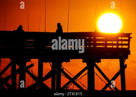 Île de Palms, États-Unis. 24 octobre 2023. Les pêcheurs silhouettés par le lever du soleil attendent que le poisson morde sur la jetée de l'île de Palms, le 24 octobre 2023 à l'île de Palms, en Caroline du Sud. Crédit : Richard Ellis/Richard Ellis/Alamy Live News Banque D'Images