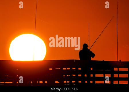 Île de Palms, États-Unis. 24 octobre 2023. Les pêcheurs silhouettés par le lever du soleil attendent que le poisson morde sur la jetée de l'île de Palms, le 24 octobre 2023 à l'île de Palms, en Caroline du Sud. Crédit : Richard Ellis/Richard Ellis/Alamy Live News Banque D'Images