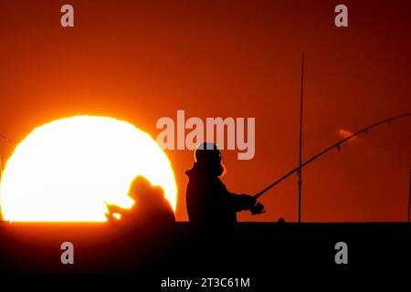 Île de Palms, États-Unis. 24 octobre 2023. Les pêcheurs silhouettés par le lever du soleil attendent que le poisson morde sur la jetée de l'île de Palms, le 24 octobre 2023 à l'île de Palms, en Caroline du Sud. Crédit : Richard Ellis/Richard Ellis/Alamy Live News Banque D'Images