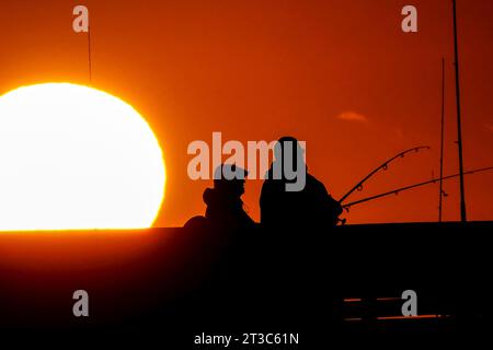 Île de Palms, États-Unis. 24 octobre 2023. Les pêcheurs silhouettés par le lever du soleil attendent que le poisson morde sur la jetée de l'île de Palms, le 24 octobre 2023 à l'île de Palms, en Caroline du Sud. Crédit : Richard Ellis/Richard Ellis/Alamy Live News Banque D'Images