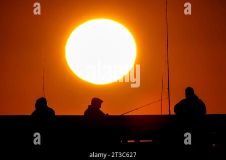 Île de Palms, États-Unis. 24 octobre 2023. Les pêcheurs silhouettés par le lever du soleil attendent que le poisson morde sur la jetée de l'île de Palms, le 24 octobre 2023 à l'île de Palms, en Caroline du Sud. Crédit : Richard Ellis/Richard Ellis/Alamy Live News Banque D'Images