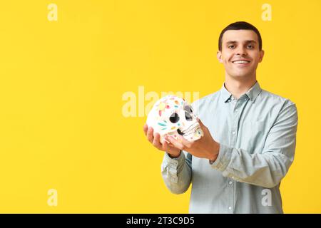 Beau jeune homme avec crâne peint sur fond jaune Banque D'Images