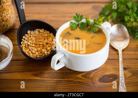 Soupe de purée de pois séchés cuite avec des champignons dans un bol sur une table en bois sombre. Banque D'Images