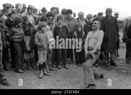 Johnny Eagle, homme fort gitan célèbre, showman et évasiologue regardé par une foule de voyageurs, déchire un livre en deux. Appleby dans Westmorland gitan cheval foire Cumbria, Angleterre juin 1981 1980S Royaume-Uni HOMER SYKES. Banque D'Images