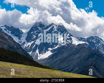 Chaînes de montagnes avec de la neige et des prairies avec des fleurs jaunes dans les hautes terres de l'est du Tibet, Chine Banque D'Images