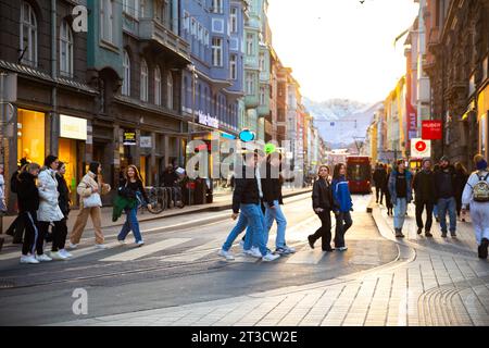 Rue de la vieille ville d'Innsbruck avec des touristes au coucher du soleil avec montagne de neige en arrière-plan Banque D'Images