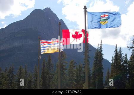 Les drapeaux provinciaux et du Canada flottent à la frontière de l'Alberta et de la Colombie-Britannique (C.-B.) lors d'une belle journée d'été dans les Rocheuses canadiennes. Banque D'Images