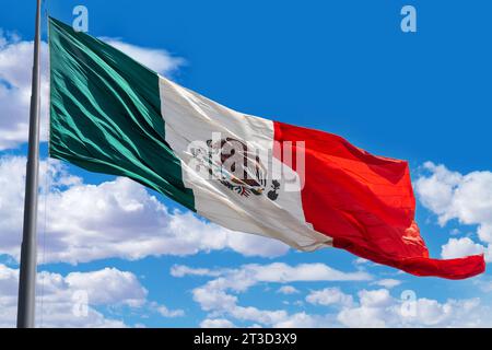 Drapeau du Mexique sur un poteau avec un fond de ciel nuageux bleu Banque D'Images