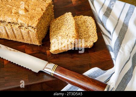 Pain aux amandes avec deux tranches sur une planche à découper en bois avec un couteau à pain Banque D'Images