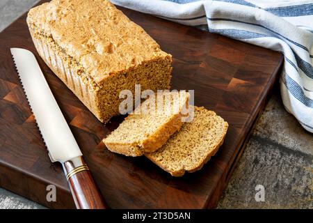 Pain aux amandes avec deux tranches sur une planche à découper en bois avec un couteau à pain Banque D'Images