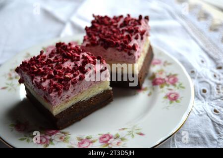 Délicieux brownies au fromage à la crème de framboise, avec des morceaux de framboise lyophilisés sur le dessus. Servi sur une assiette en porcelaine vintage Banque D'Images