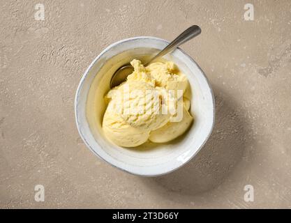 gros plan du bol de crème glacée vanille sur la table de couleur beige, vue de dessus Banque D'Images