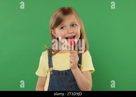 Portrait de fille mignonne léchant sucette sur fond vert Banque D'Images