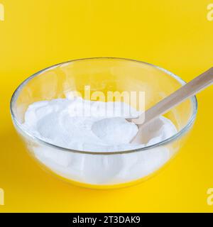 Bicarbonate de soude dans un bol, sur fond jaune Banque D'Images