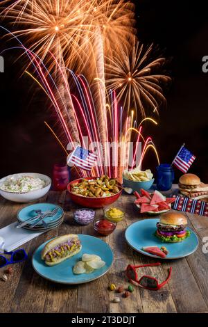 Barbecue du 4 juillet avec feux d'artifice en arrière-plan sur une table en bois Banque D'Images