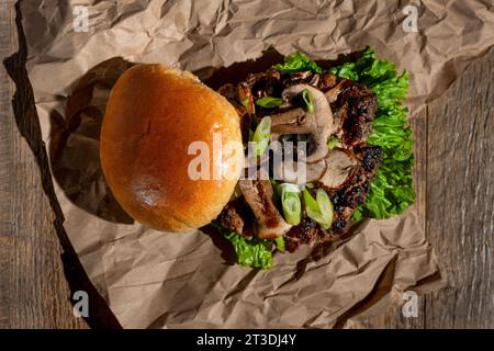 Un gros plan de smash Burger avec des champignons sur une table en bois Banque D'Images