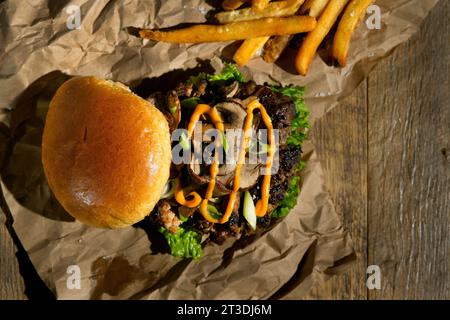 Smash Burger avec des champignons et des frites sur une table en bois Banque D'Images