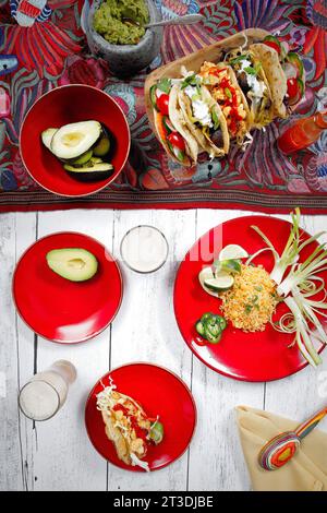 Une variété de tacos sur des assiettes sur une table en bois avec un design de toile de table Banque D'Images