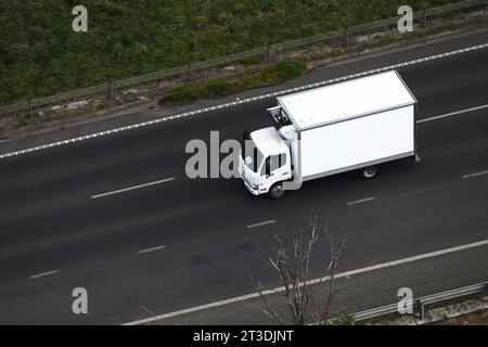 Vue aérienne d'un camion blanc de livraison de chambre froide sur une autoroute, montrant le transport et la distribution. Banque D'Images