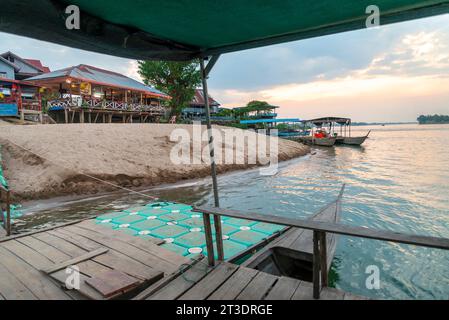 Au coucher du soleil, sur le fleuve Mékong, petits bateaux en bois transportant des voyageurs vers et depuis les îles Nakasong et Don Som, au point de jetée de plage de sable, passerelle principale Banque D'Images