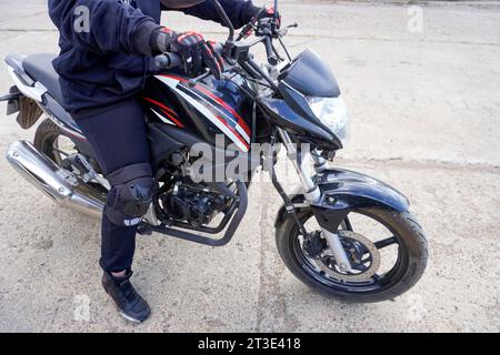 femme motocycliste dans un casque, gants de moto, bottes de moto sur un gros plan de moto Banque D'Images