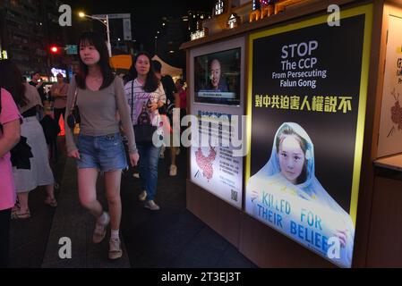 ** STRICTEMENT AUCUNE VENTE AUX MÉDIAS OU ÉDITEURS FRANÇAIS - DROITS RÉSERVÉS ***01 octobre 2023 - Taipei, Taiwan : des jeunes taïwanais sortent dans le quartier de Ximending, marchent devant les panneaux d'affichage du Falun Gong dénonçant les crimes du Parti communiste chinois contre le groupe. Banque D'Images
