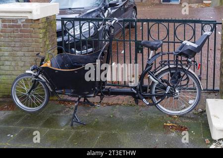 vélo cargo noir garé sur un trottoir Banque D'Images