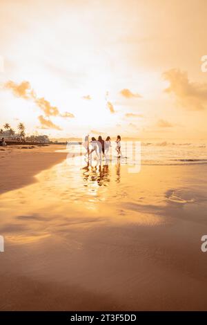 Un groupe de femmes asiatiques court avec leurs amis heureux sur la plage dans l'après-midi Banque D'Images