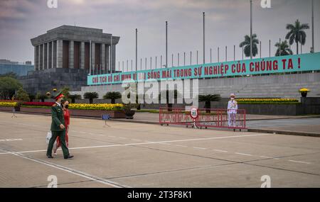 Un soldat vietnamien en en uniforme et une femme en ao dai traditionnelle marchent devant le mausolée Ho Chi Minh sur la place Ba Dinh, Hanoi, Vietnam. Banque D'Images