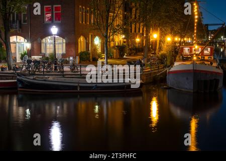 Pays-Bas. Nuit d'été à Amsterdam. Remblai du canal avec péniches et vélos Banque D'Images