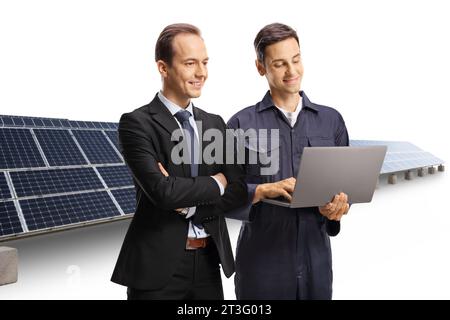 Homme d'affaires et un technicien regardant un ordinateur portable devant le photovoltaïque isolé sur fond blanc Banque D'Images