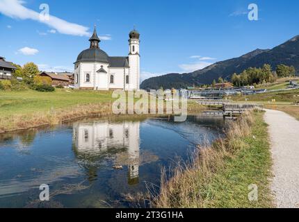 19.10.2023/Seefeld in Tirol, Österreich/Bild : Seekirche Heiliges Kreuz, Seekirchl, Heiligkreuzkirche/vorne : Raabach, kleiner Bach/re. : Kongresszentrum Seefeld, Olympia Kongress, Olympiakongresszentrum, Olympia Sport- und Kongresszentrum, Olympiabad Segressund/im: Skigebiet Rosshütte im Herbst *** 19 10 2023 Seefeld in Tirol, Autriche photo lac église Heiliges Kreuz, Seekirchl, Heiligkreuzkirche en face Raabach, petit ruisseau RE centre de congrès Seefeld, Olympia congrès, Olympia congrès, Olympia sport et centre de congrès, Olympiabad Seefeld en arrière-plan re ski A. Banque D'Images