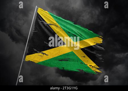 Jamaïque drapeau déchiré sur fond de ciel sombre. Banque D'Images
