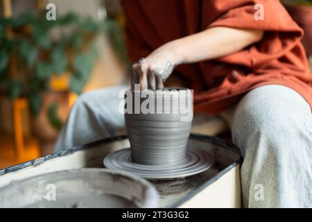Craftswoman céramiste mains sculptent l'argile humide formant le produit final fait à la main sur la roue de poterie pour la commande Banque D'Images