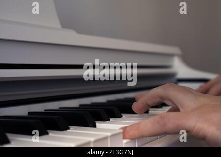 Mains masculines jouant sur un piano droit blanc. Thème musical. Clavier de piano Banque D'Images