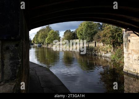 La vue à travers un pont de pierre traversant le canal Calder & Hebble navigation près de Mirfield, West Yorkshire par un jour calme d'automne Banque D'Images