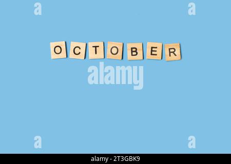 Mot d'octobre fait avec des blocs de lettre en bois sur un fond bleu avec espace de copie Banque D'Images