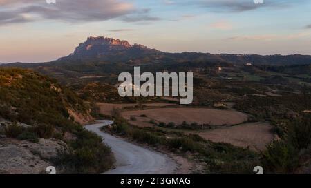 Les rayons du soleil couchant touchent Montserrat. Le paysage rural ci-dessous se trouve dans l'ombre. Banque D'Images