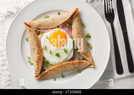 Crêpe bretonne, sarrasin salé galettes Bretonnes avec oeuf frit, fromage, jambon closeup sur l'assiette sur la table. Vue de dessus horizontale Banque D'Images