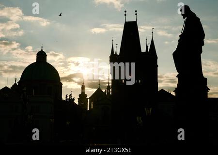 République tchèque, Bohême, Prague, centre historique inscrit au patrimoine mondial de l'UNESCO, quartier de Staré Město (vieille ville), statue sur le pont Charles (Karluv Most) avec la tour gothique et le dôme de l'église Saint-François d'Assise et la statue de Saint Joseph et de l'enfant Jésus en contre-jour Banque D'Images