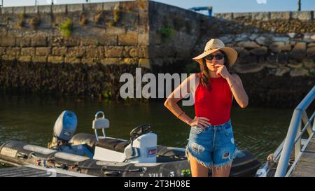 jeune fille sérieuse regardant la caméra avec un fond de zodiac de bateau à moteur dans le port maritime Banque D'Images