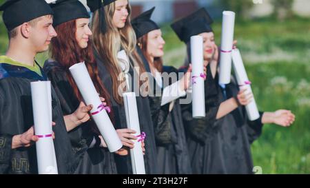 Rouleaux de diplômes entre les mains d'un groupe de diplômés. Banque D'Images