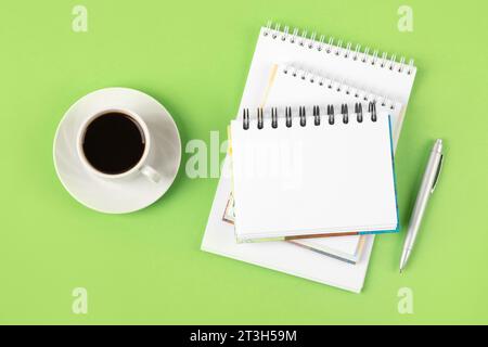 Composition avec bloc-notes vierge ouvert et stylo, tasse de café noir sur fond vert. Tasse à café du matin. Faire des plans, des objectifs pour l'avenir Banque D'Images