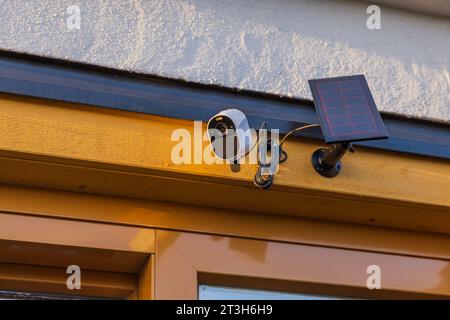 Vue rapprochée de la caméra de sécurité extérieure high-tech équipée d'un panneau solaire monté sur la façade de la villa. Suède. Banque D'Images